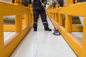 Worker cleaning floor in aluminium factory