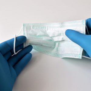 Technician holding a mask for personal protective equipment during disinfecting services